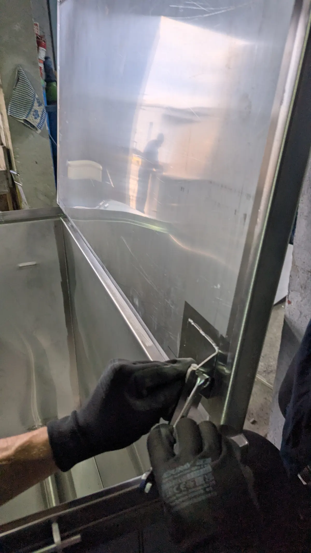 Mâini în mănuși fixând un nit pe un element din inox