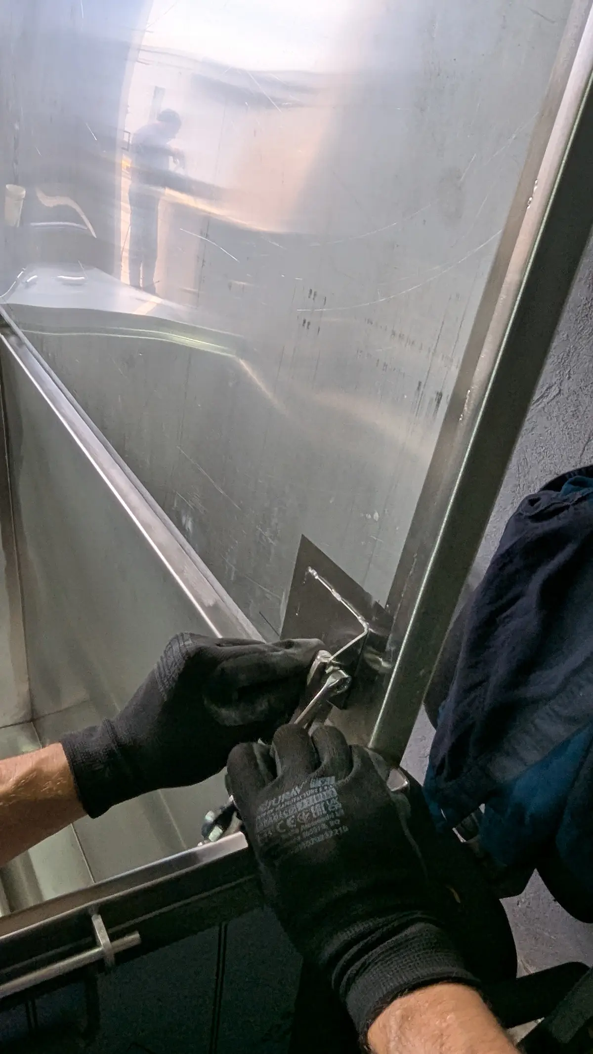 Mâini în mănuși fixând un nit pe un element din inox